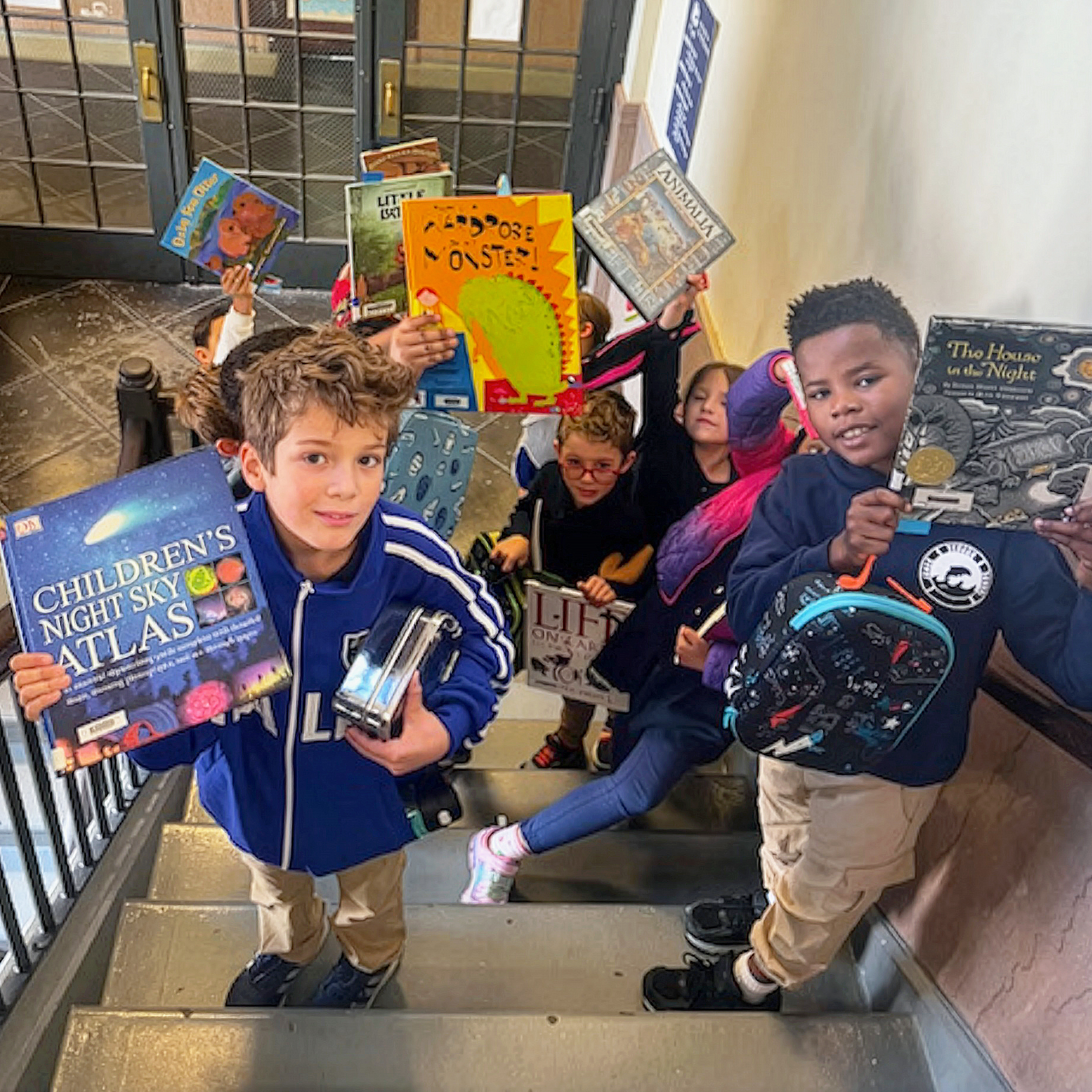 Students holding books on a school stairwell.